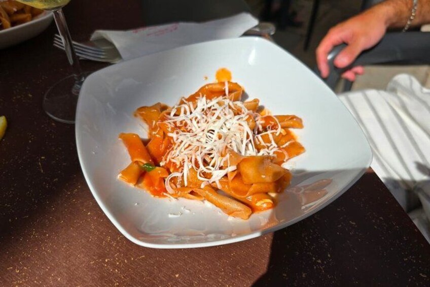 A white plate of pasta with tomato sauce and grated cheese. 3