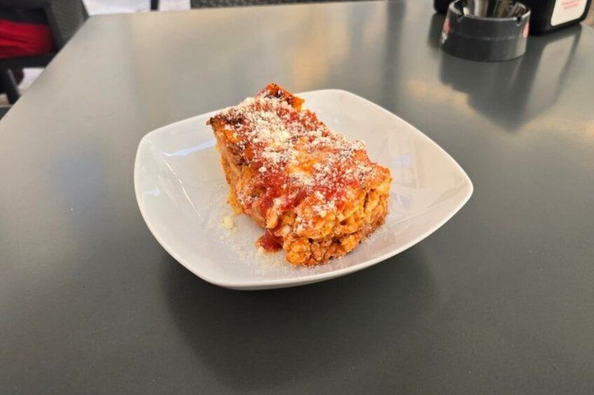 A slice of lasagna on a white plate on a table. 2