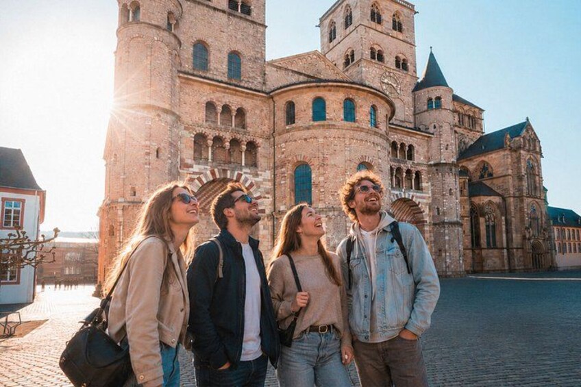 A group of people standing in front of a historic building with a large tower and arched windows. 1