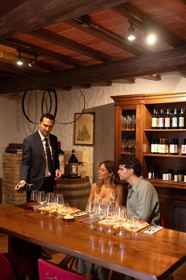 A wine tasting event with a wooden table, wine glasses, and bottles. 1