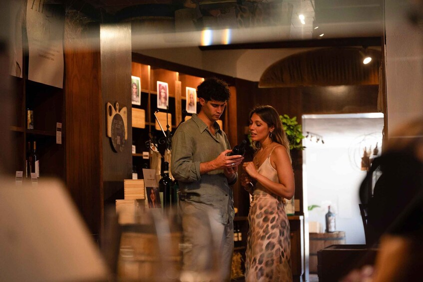 A man and a woman in a dimly lit bar, holding drinks. 4