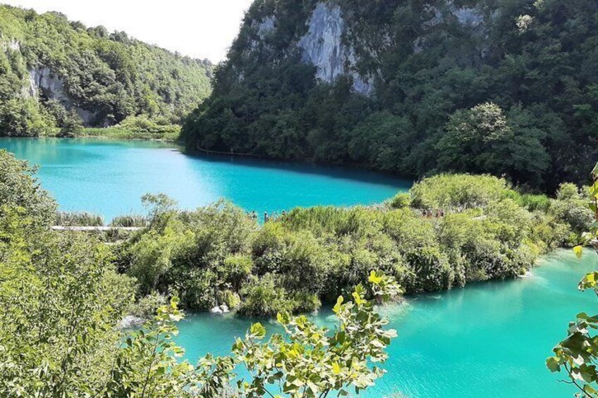 A turquoise lake surrounded by lush greenery and rocky cliffs. 1