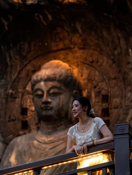 A person leaning on a railing with a large Buddha statue in the background. 5