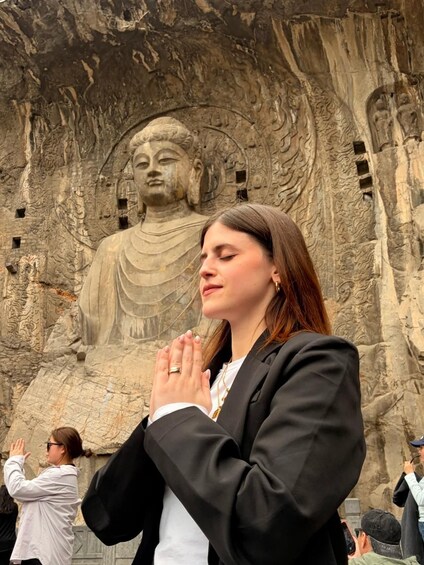 A person in front of a large stone statue with intricate carvings. 2