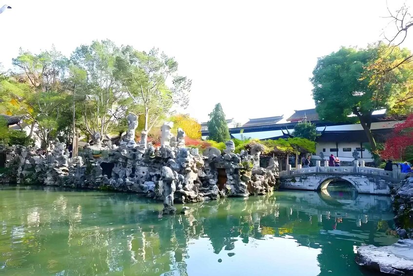 A tranquil pond with a stone bridge and traditional architecture in the background. 4