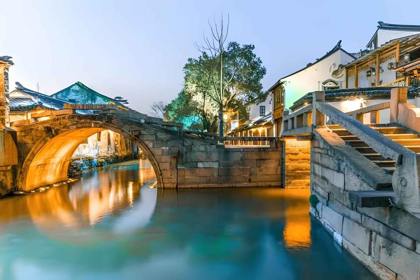 A stone bridge over a calm river, traditional buildings, and a tree in the background. 5
