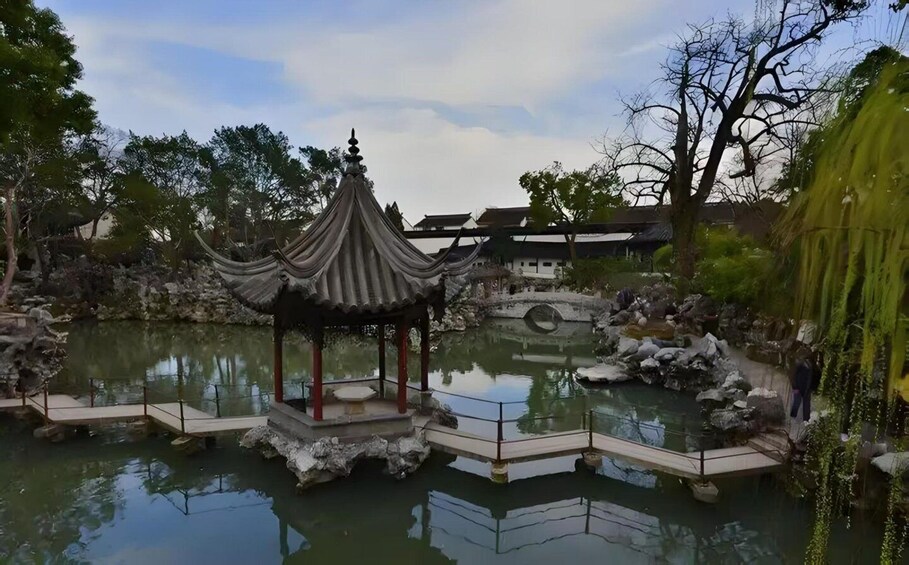 A traditional pavilion over a pond, surrounded by rocks and trees. 2