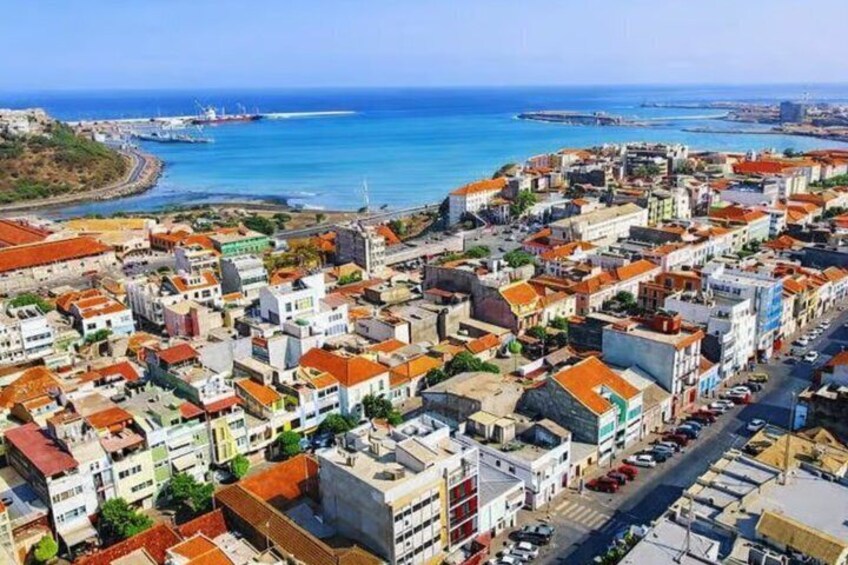 A coastal town with buildings, a harbor, and the sea. 1