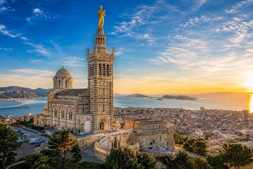 A coastal cityscape with a prominent cathedral and a tall tower with a statue. 3