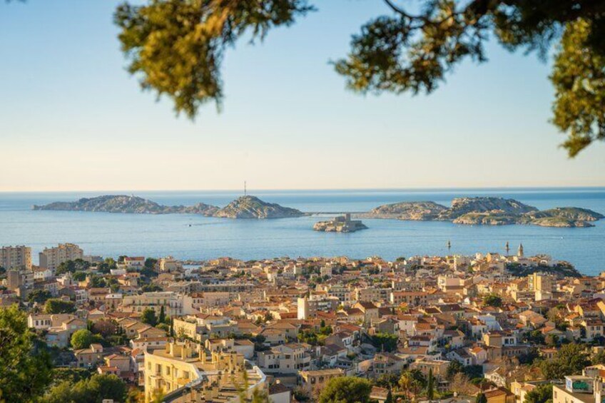 A coastal cityscape with buildings, a clear sky, and islands in the distance. 1