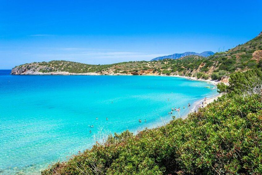 A coastal landscape with clear turquoise waters, a sandy beach, and green vegetation. 1