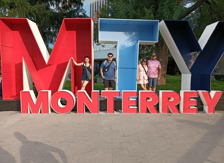 Large red and blue letters spelling 'MTY MONTERREY' with people standing in front. 1