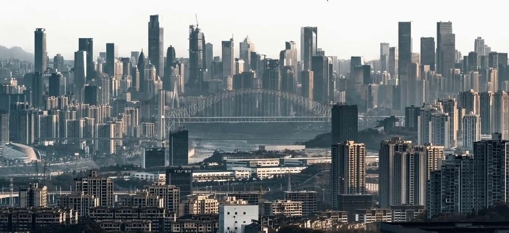 A cityscape with numerous high-rise buildings, a prominent bridge in the background, and a stadium. 3