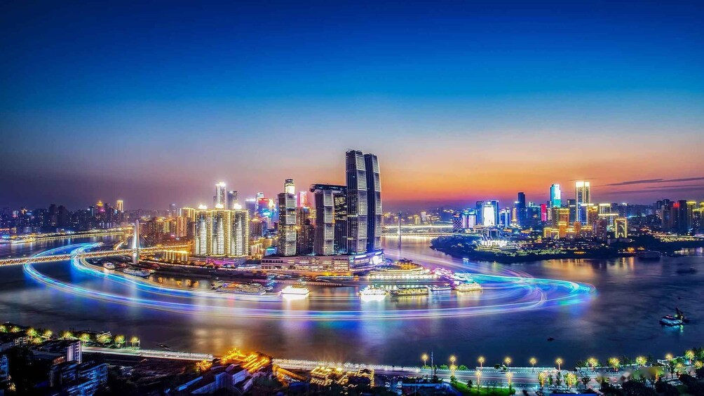 A cityscape at night with illuminated buildings, a river, and a bridge. 2