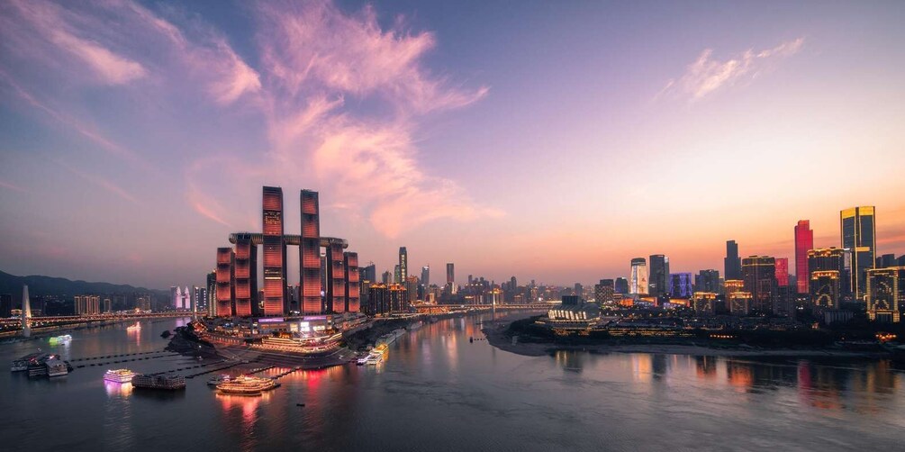 A cityscape at dusk with illuminated skyscrapers and a river reflecting the lights. 4