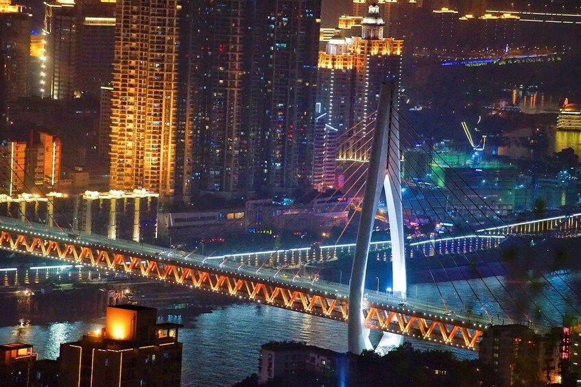 A nighttime cityscape with a prominent cable-stayed bridge and illuminated buildings. 1