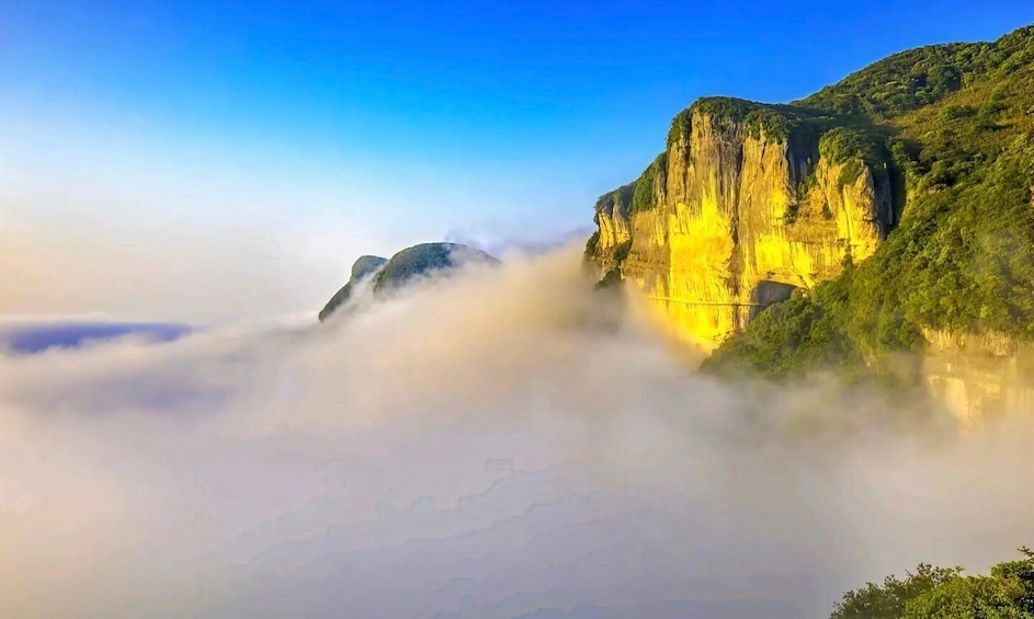 A mountain landscape with a cliff and a valley shrouded in mist. 1
