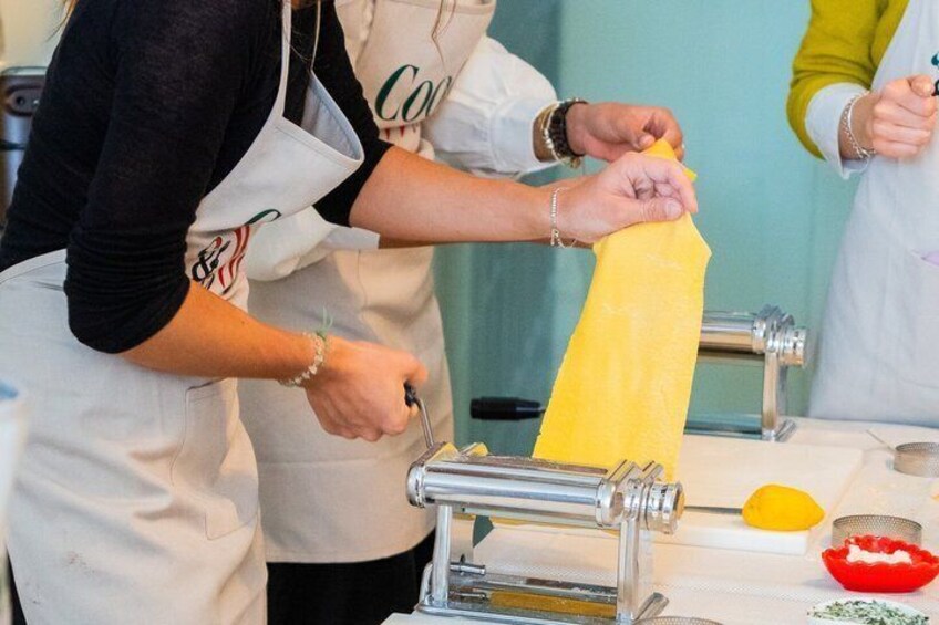 A person using a pasta machine to roll out dough. 3