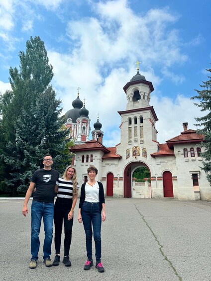 A group of people standing in front of a church with multiple domes and a bell tower. 3