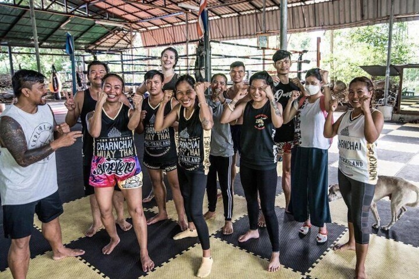 A group of people in a covered outdoor area with mats on the floor, some wearing athletic clothing. 5