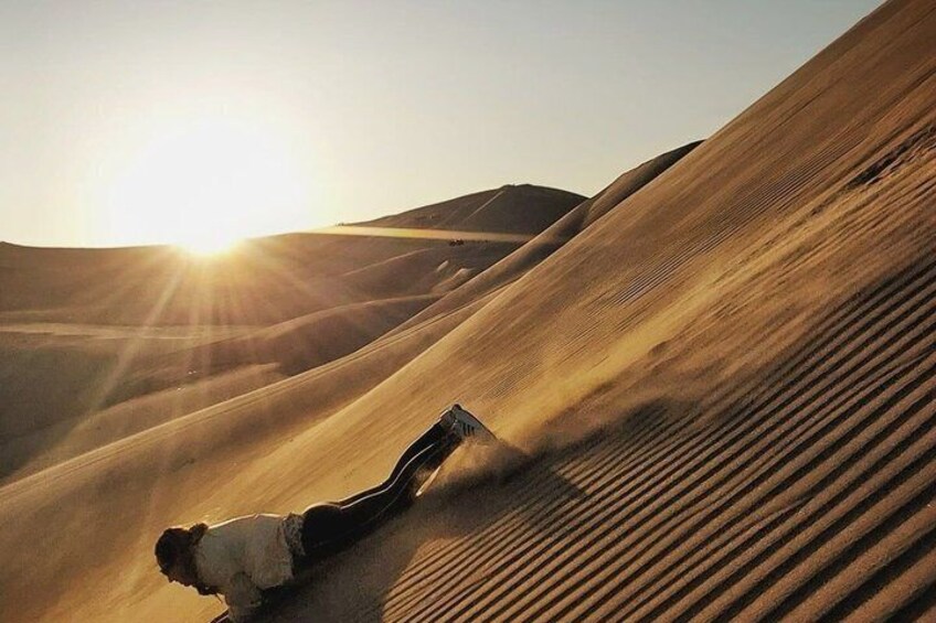 A person lying on a sand dune with the sun shining in the background. 5