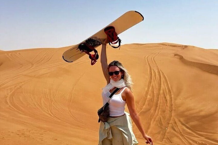 A person holding a snowboard in a desert landscape. 3