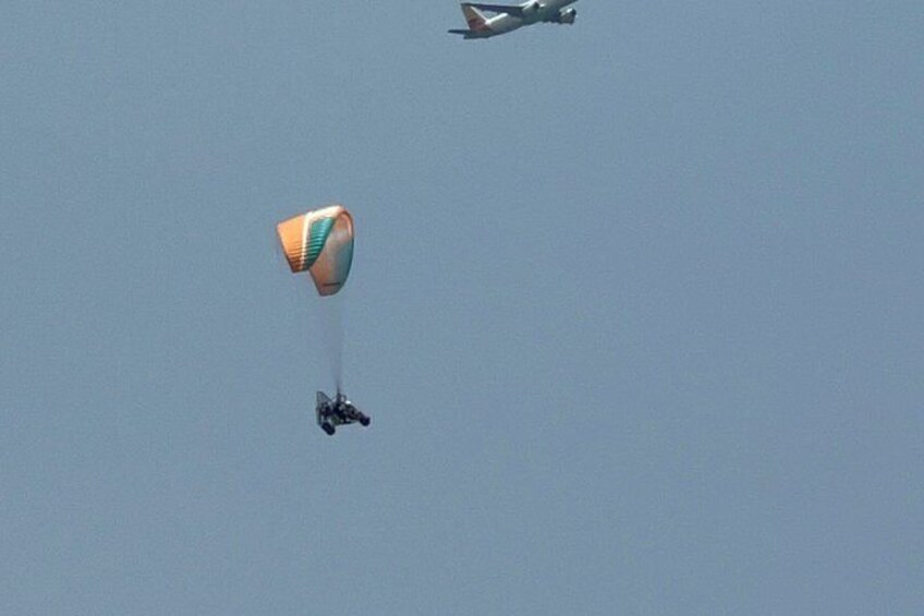 A parachute with a person and a plane in the sky. 4