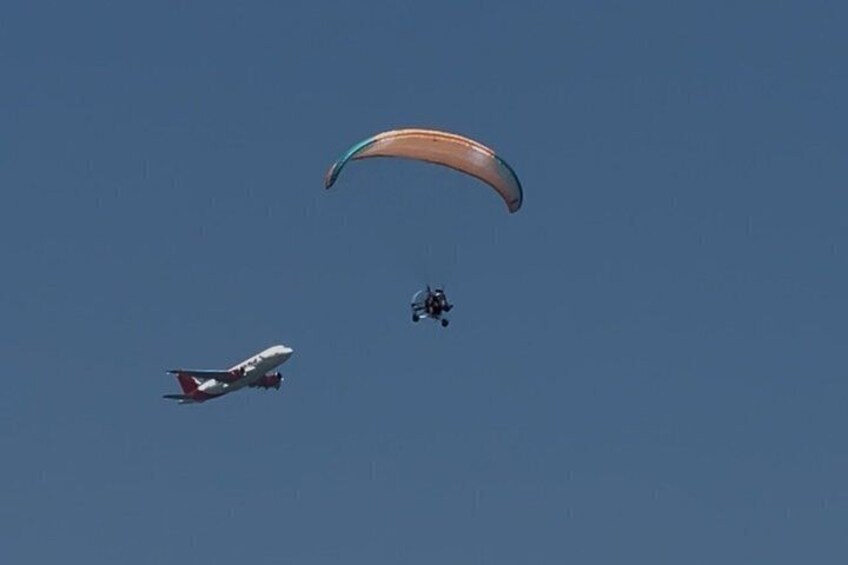 A paraglider and an airplane in the sky. 5