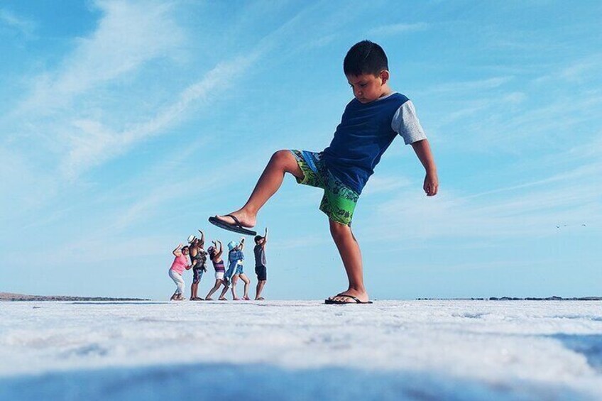 A child balancing on one leg on a flat surface with a clear sky in the background. 1