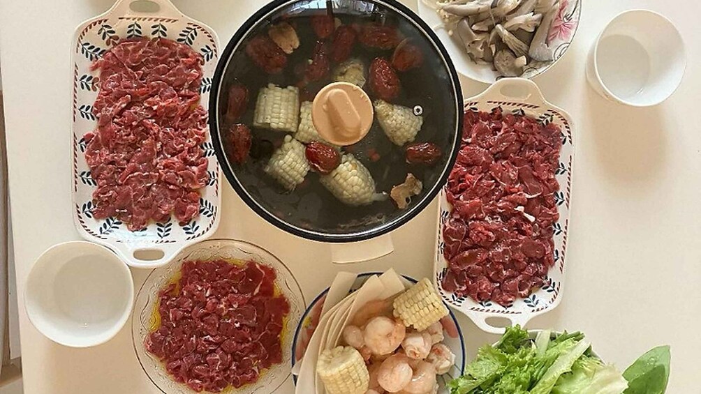 A pot with corn and meat, surrounded by bowls of meat and vegetables. 5
