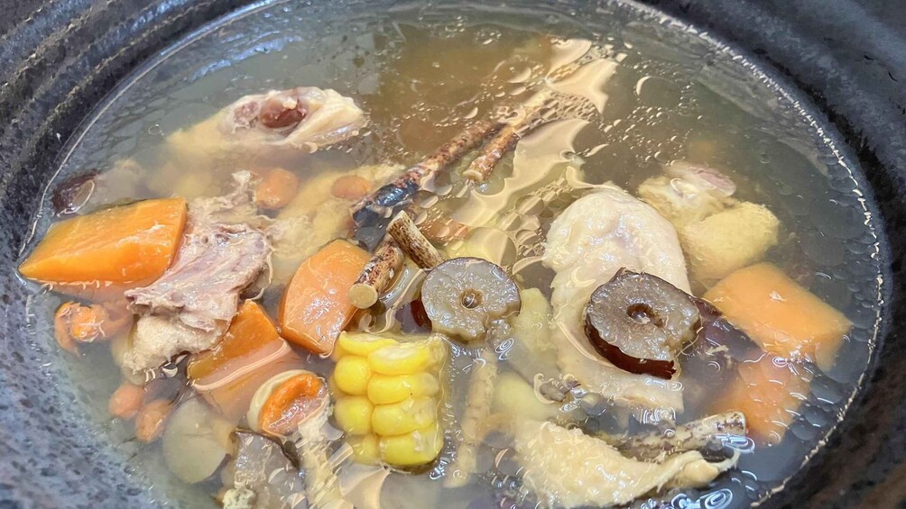 A stew with various ingredients like meat, corn, and carrots in a pot. 2