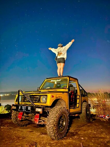 A person standing on a yellow off-road vehicle with a starry sky in the background. 2