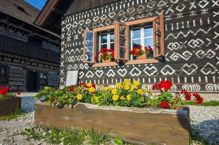 A building with a patterned exterior, a wooden window, and a flower bed with red and yellow flowers. 4