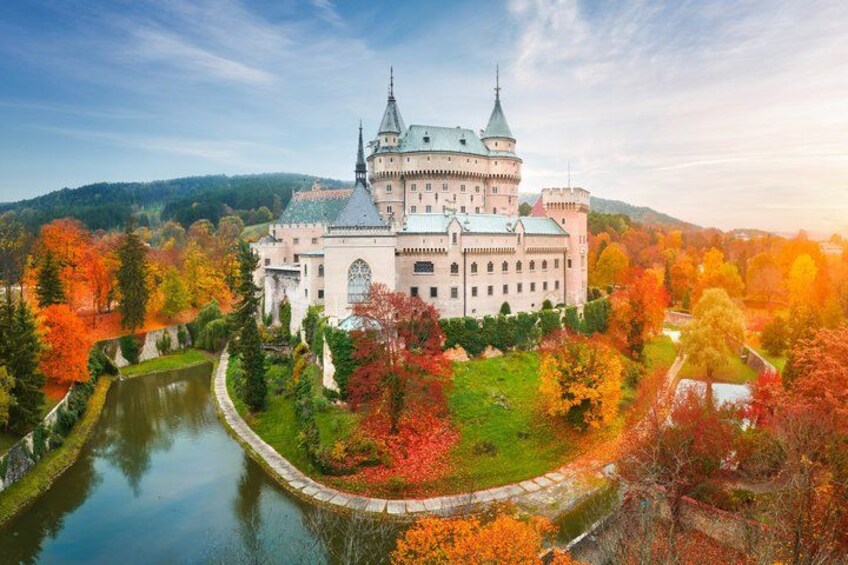 A castle surrounded by autumn foliage and a river. 2