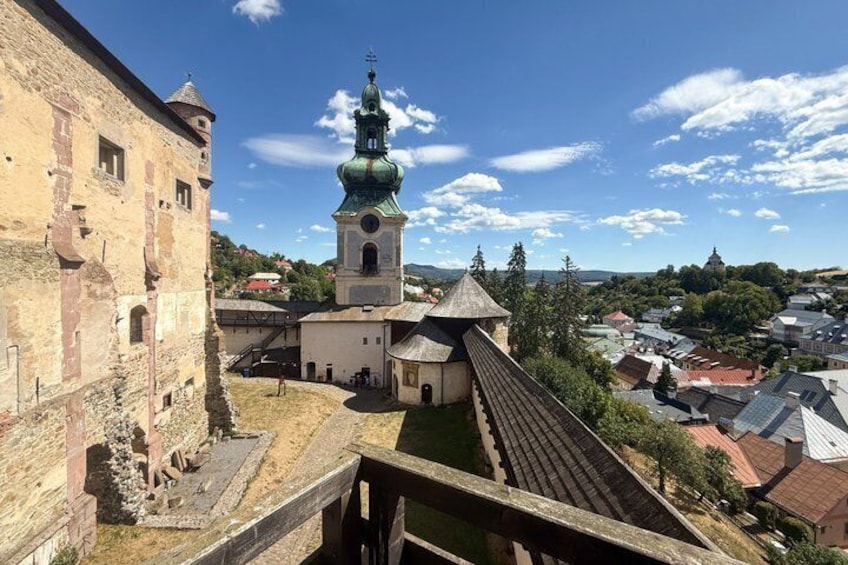 A historic building with a green dome, a stone bridge, and a town in the background. 5