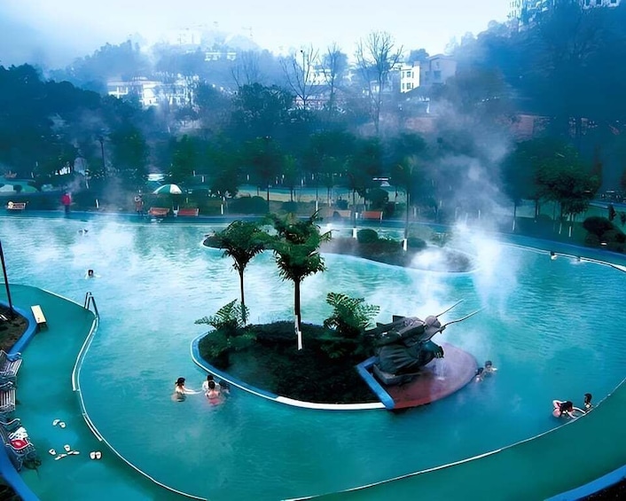 A swimming pool with a central island, surrounded by lounge chairs and people swimming. 1