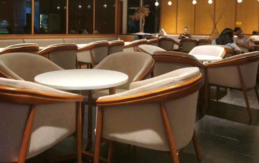 A restaurant interior with round tables and cushioned chairs. 2
