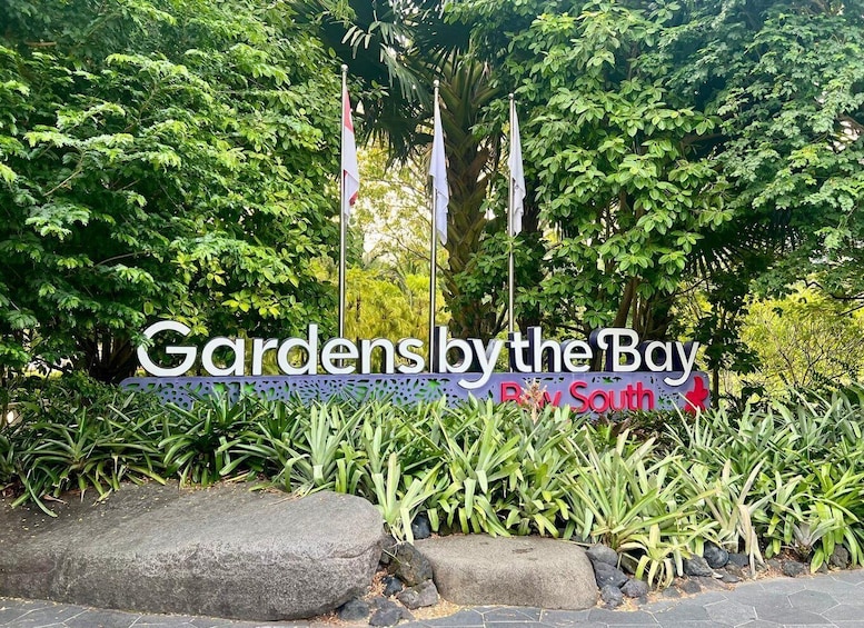 A sign for 'Gardens by the Bay' with lush greenery and rocks in the foreground. 2