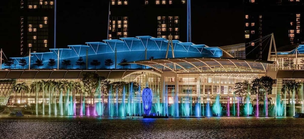 A waterfront building with a glass facade and a series of fountains. 5