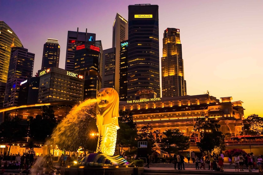 A cityscape at dusk with illuminated skyscrapers, including HSBC and Maybank, and a large statue in the foreground. 3