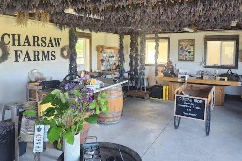 A rustic interior with a sign reading 'CHARSAW FARMS,' a wooden barrel, and a chalkboard menu. 5