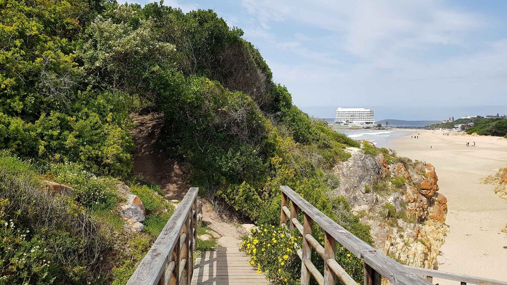 A wooden boardwalk leading to a beach with a building in the background. 1
