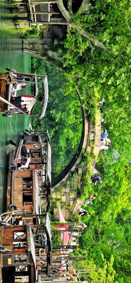 A riverside area with boats docked, a wooden walkway, and lush greenery. 2