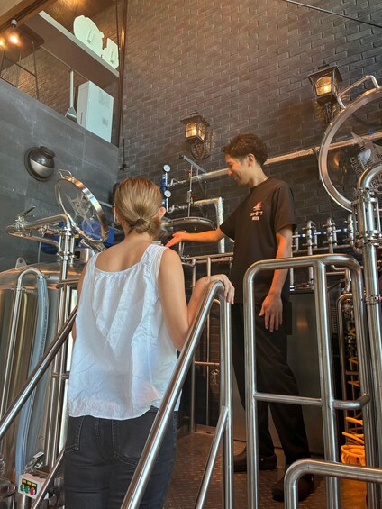 A person in a white top and jeans standing next to a metal structure with a person in a black shirt. 1