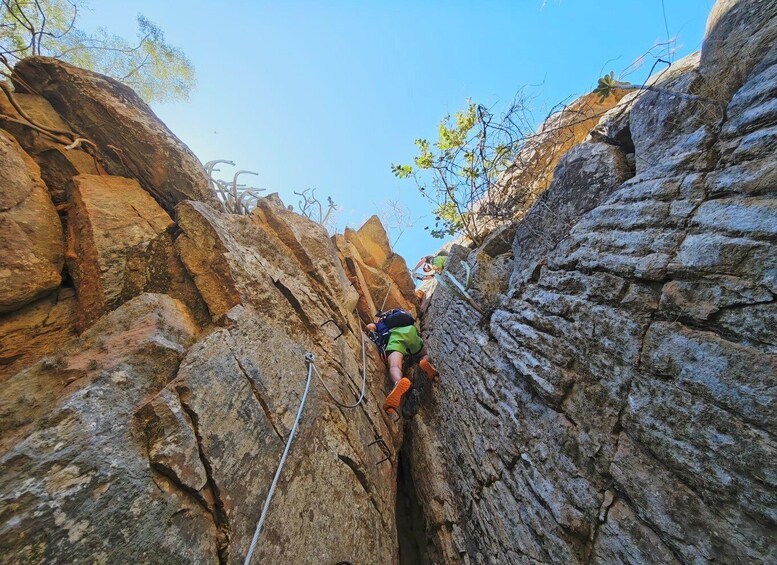 A person climbing a rocky cliff with ropes. 4