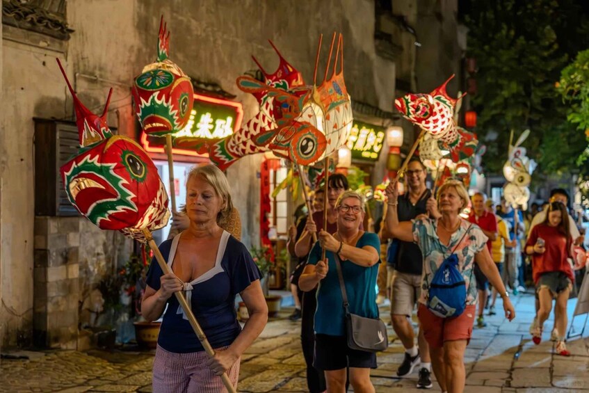 A group of people walking down a street at night, holding colorful dragon-shaped lanterns. 1