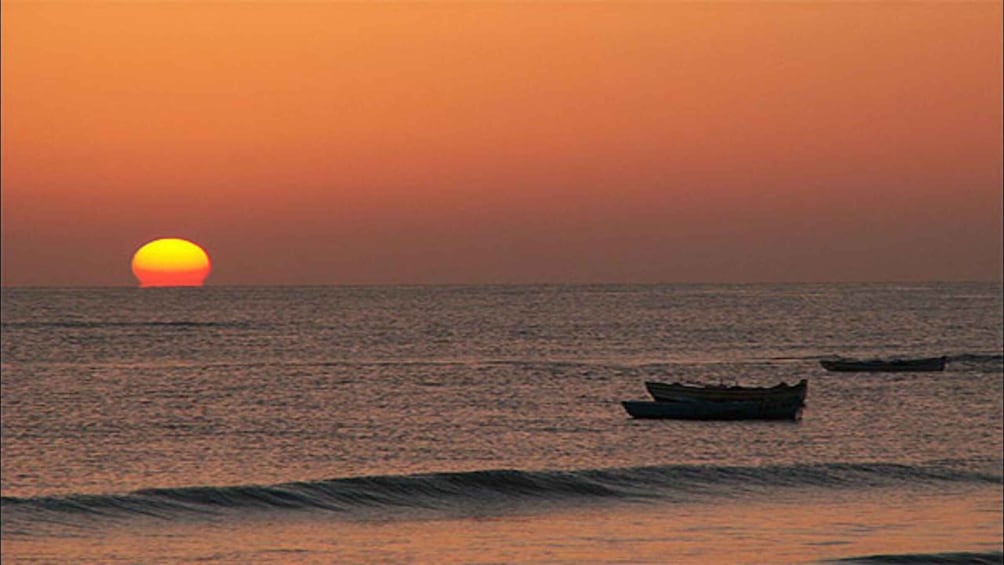 A sunset over the ocean with a boat in the water. 1
