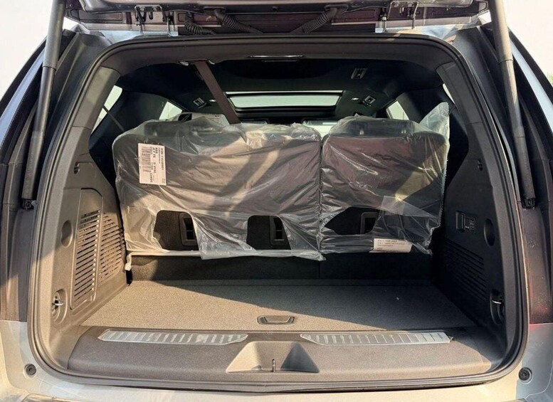 A car trunk with two large, covered objects. 3