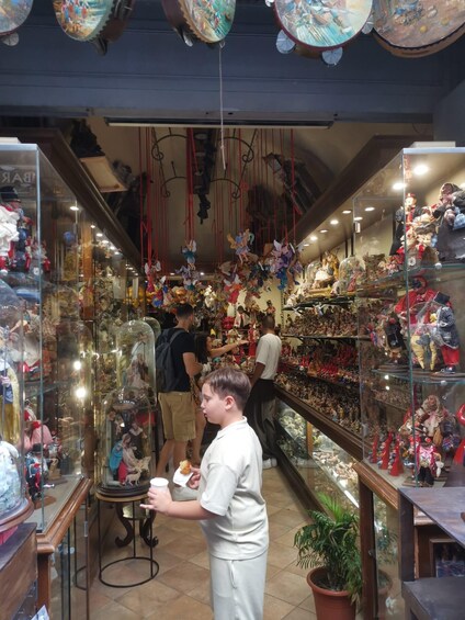 A narrow indoor market with glass display cases filled with various items. 3