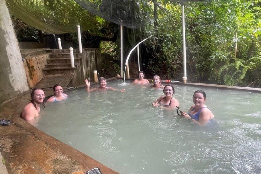 A group of people in a natural hot spring surrounded by greenery. 5